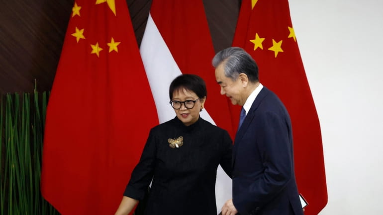 Chinese Foreign Minister Wang Yi, right, walks with Indonesian Foreign...