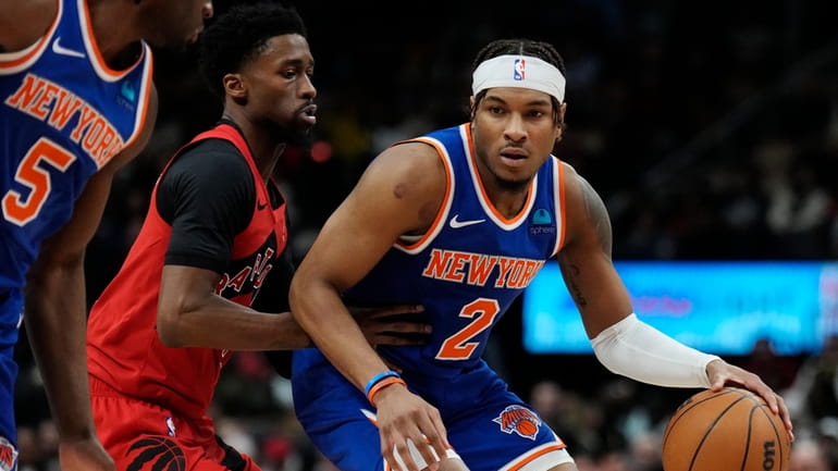 Knicks guard Miles McBride protects the ball from Raptors guard Kobi...