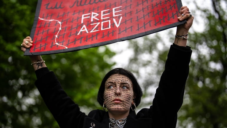 A woman holds a "Free Azov" sign during a rally...