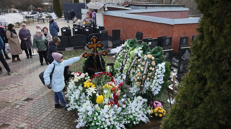 A woman touches a cross at the grave of Russian...