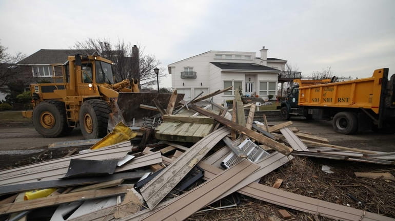 Village of Lindenhurst workers use heavy machinery to remove debris...