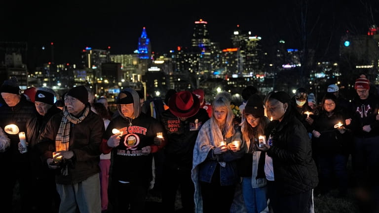 People attend a candlelight vigil for victims of a shooting...