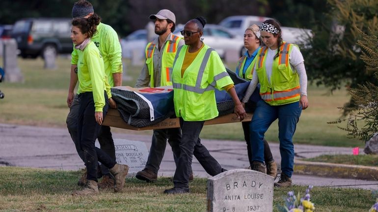 Researchers and burial oversight committee member Brenda Alford carry the...