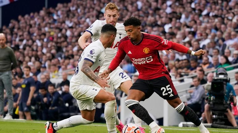 Manchester United's Jadon Sancho, right, and Tottenham's Pedro Porro challenge...