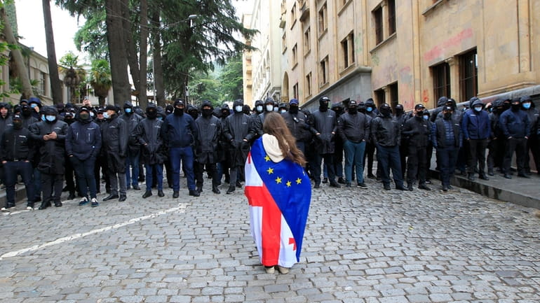 A demonstrator with draped Georgian national and EU flags stands...