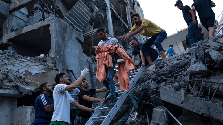 Palestinians rescue a young girl from the rubble of a...