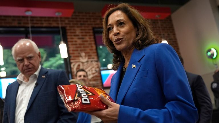 Democratic presidential nominee Vice President Kamala Harris holds a bag...