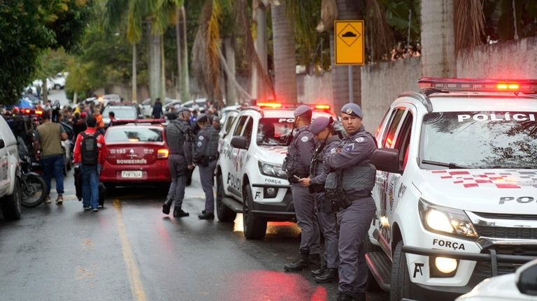 Police stand along the street leading to the gated community...