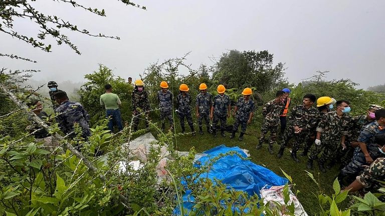 Rescuers stand by bodies recovered from the site of a...