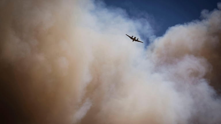 An air tanker soars through a large plume of smoke...