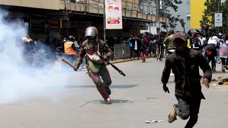 A police officer chases demonstrators during a protest in Nairobi,...