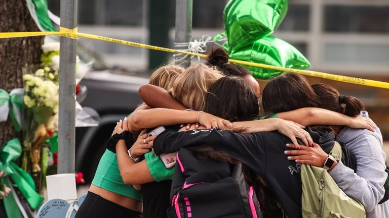 Students and faculty embrace at a memorial outside Farmingdale High...