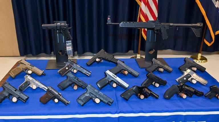 Some of the guns seized are displayed at a news...