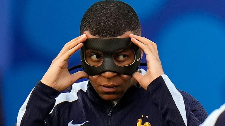 Kylian Mbappe of France adjusts his face mask as the...
