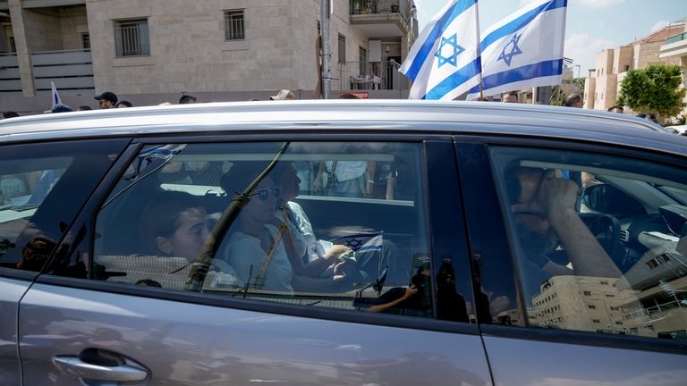 Mourners wave Israeli flags as they accompany the family of...