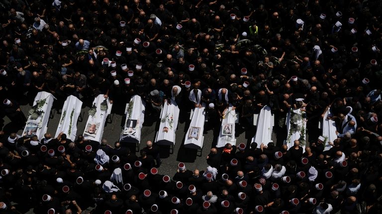 Mourners from the Druze minority surround the bodies of some...