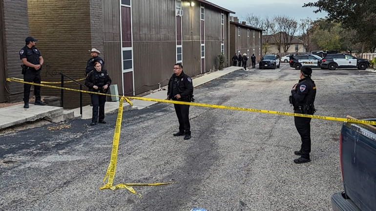 Police rope off the scene where two dead bodies were...