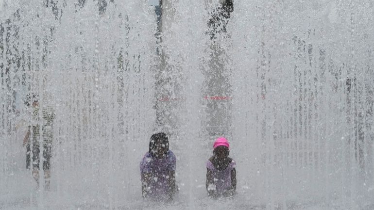 Children cool themselves off in a public fountain in Seoul,...