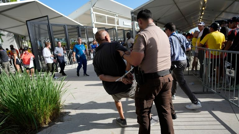 A man is detenied by police outside the stadium prior...