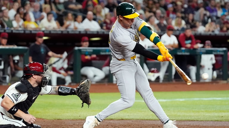 Oakland Athletics' Brent Rooker, right, connects for a run-scoring single...