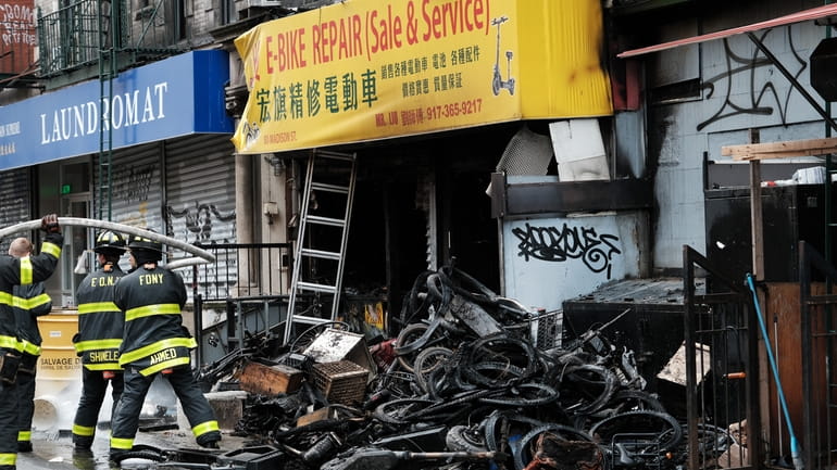 Firefighters work at a Chinatown building where four people were killed...