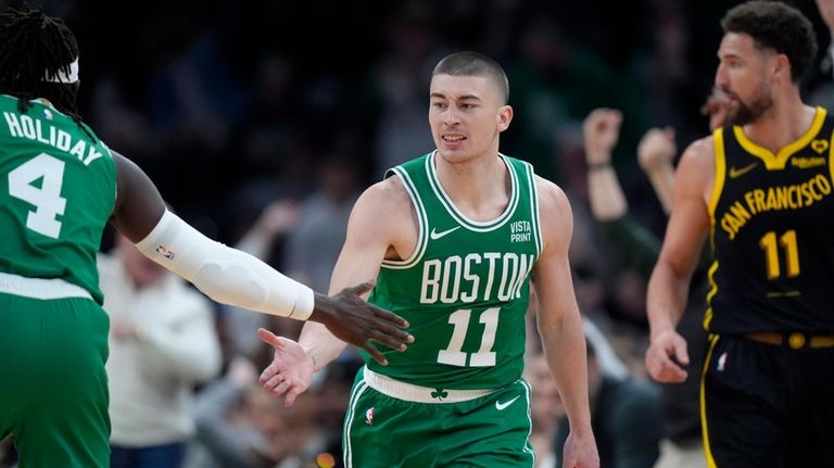 Boston Celtics guard Payton Pritchard, center, celebrates with guard Jrue...