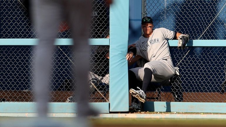 Aaron Judge #99 of the New York Yankees crashes through...