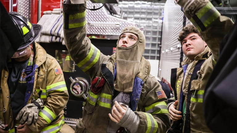 Volunteer firefighter Spencer Gray, 20, center, gears up alongside his...