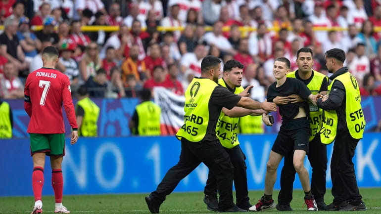 Stewards catch a pitch invader that ran to Portugal's Cristiano...