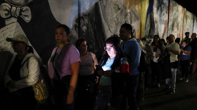 Voters line up at a voting station prior to the...