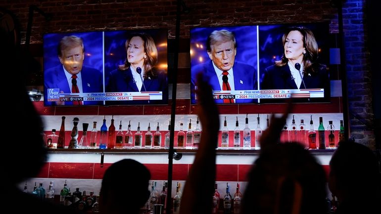 Viewers cheer as they watch a debate between Democratic presidential...