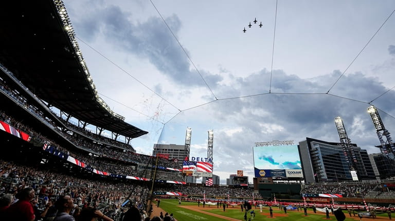 Military aircraft fly over Truist Park before a baseball game...