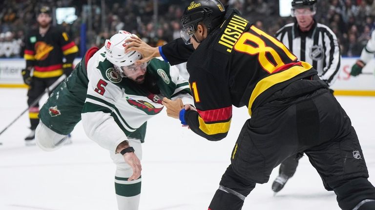 Minnesota Wild's Jacob Middleton, left, and Vancouver Canucks' Dakota Joshua...