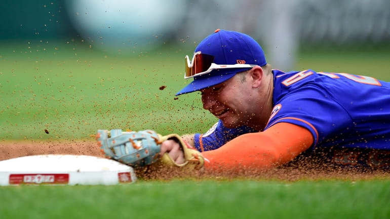 The Mets' Pete Alonso dives to tag first base for...