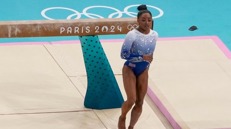 Simone Biles, of the United States, falls on the beam...