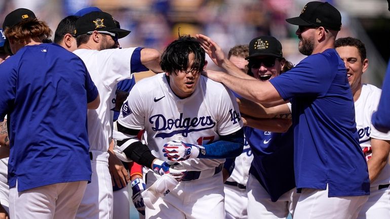 Los Angeles Dodgers' Shohei Ohtani, center, is congratulated by teammates...