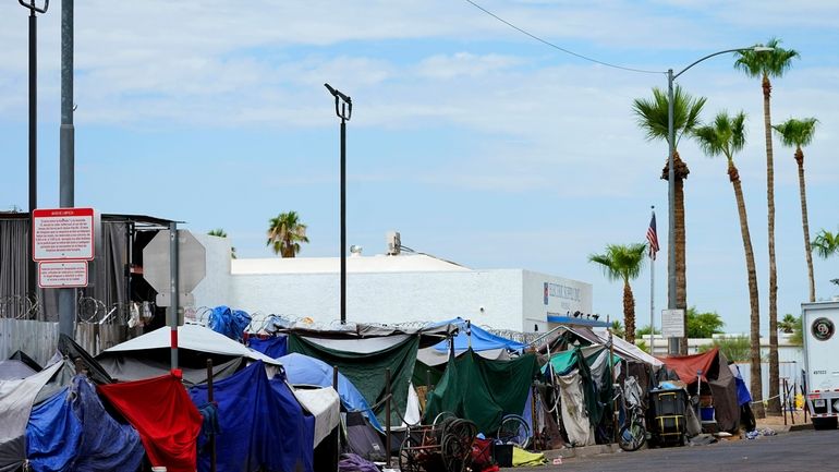 Tents line the street of "The Zone," a homeless encampment,...