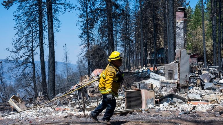 A firefighter walks by the remains of a home that...