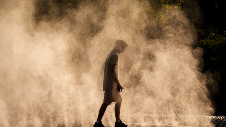 A young man cools off in the drizzle from a...