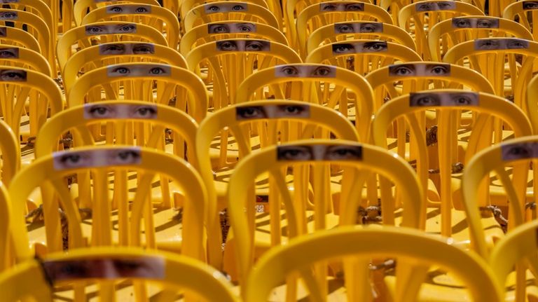 Images of human eyes are placed on empty chairs tied...