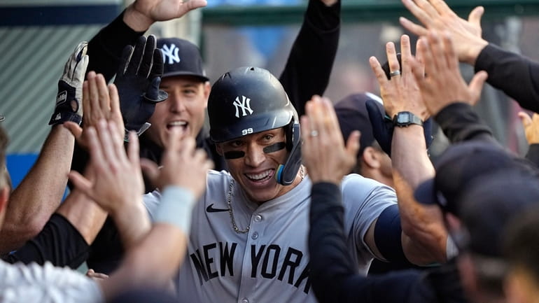 Yankees' Aaron Judge is congratulated by teammates in the dugout...