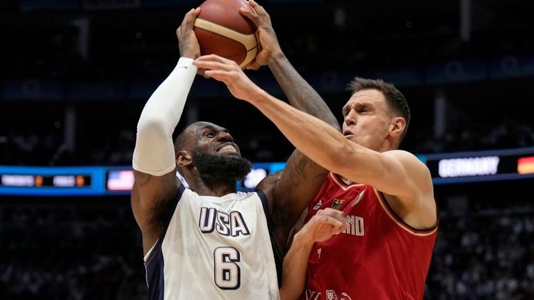 Germany's Johannes Voigtmann, right, blocks United States' forward LeBron James...