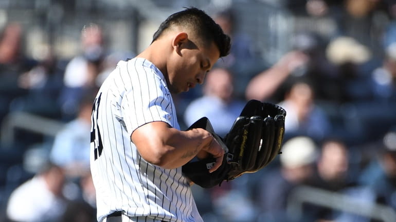 Yankees relief pitcher Jonathan Loaisiga adjusts the PitchCom receiver in...