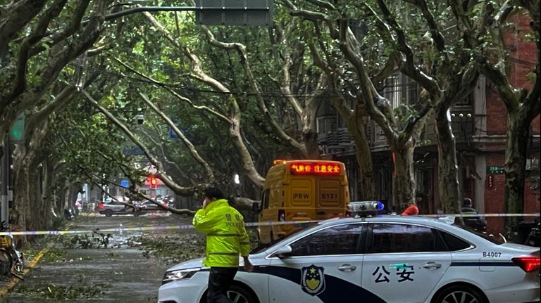 Policemen closed a road as fallen trees along a street...