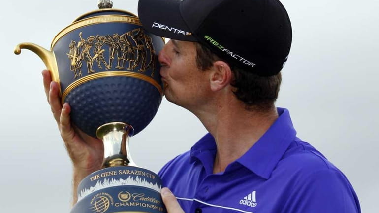 Justin Rose, of England, kisses the trophy after he won...