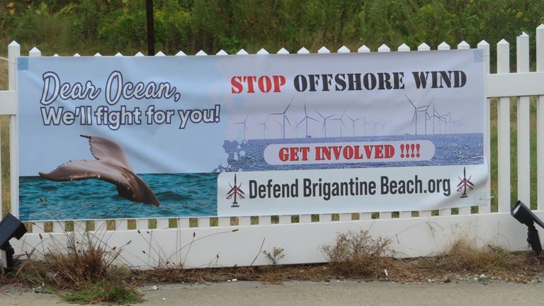 An anti-offshore wind sign is draped across a fence in...