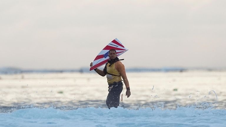 A water safety team member stands on the reef holding...