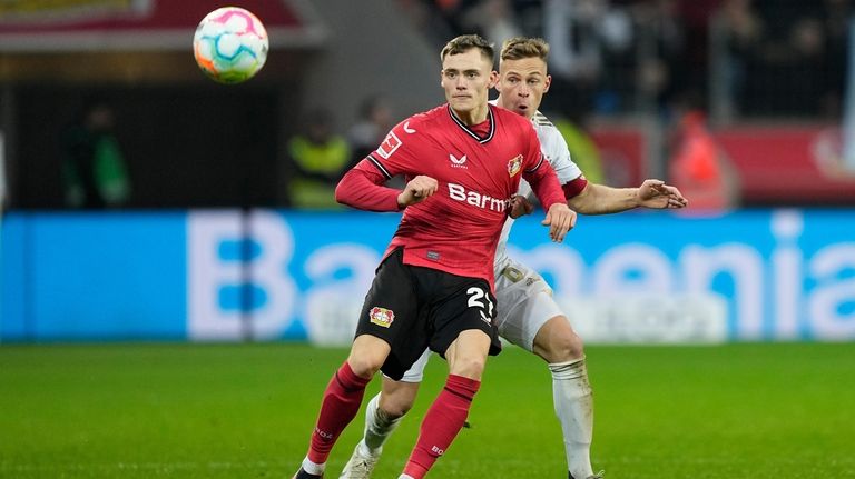 Leverkusen's Florian Wirtz, left, and Bayern's Joshua Kimmich, right, challenge...