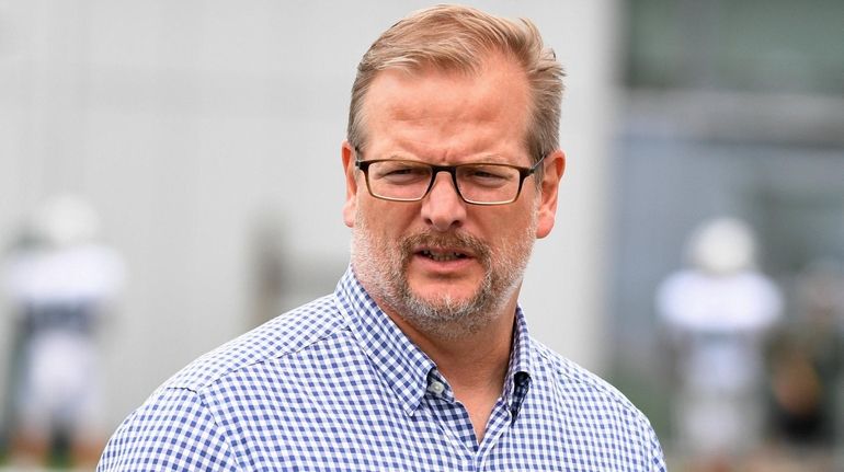 Mike Maccagnan walks from the field after practice during training...