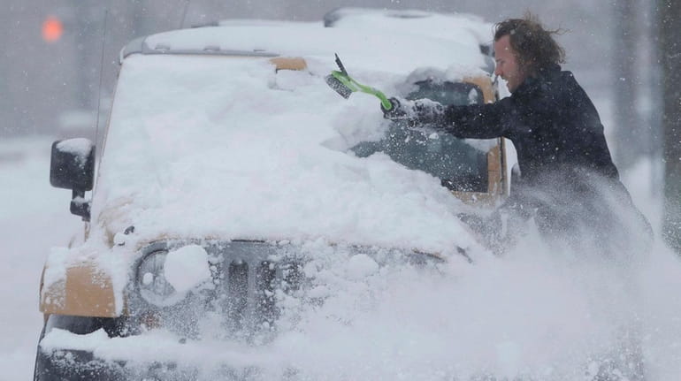 An unidentified motorist clears snow off his four-wheel-drive vehicle in...